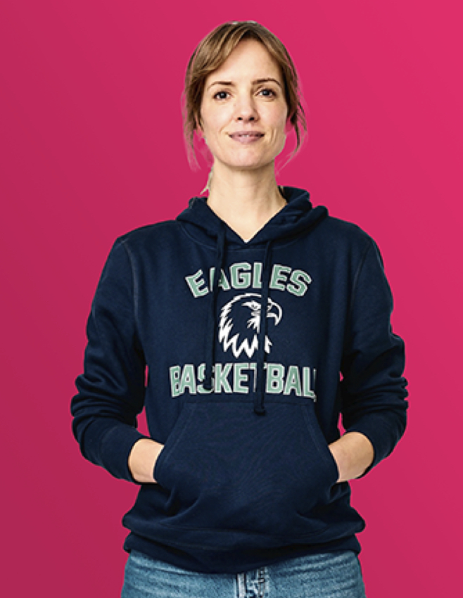 Woman with hands in pockets on pink background